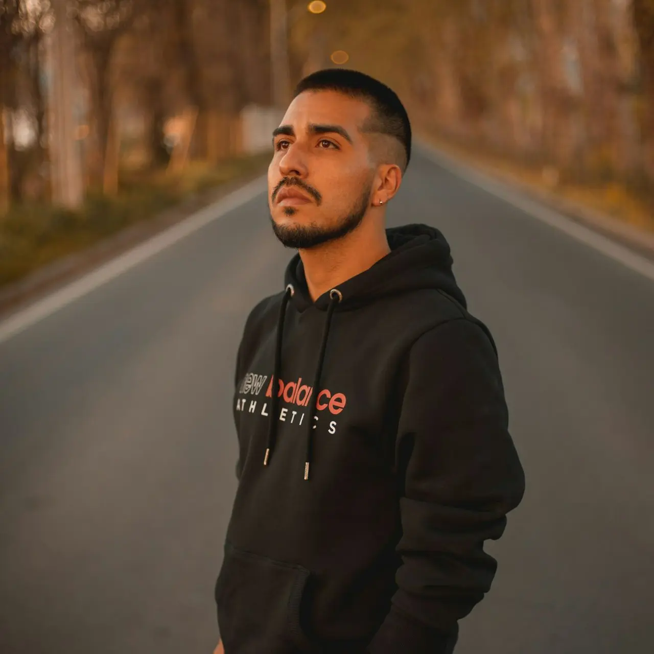man in black hoodie standing on road during daytime